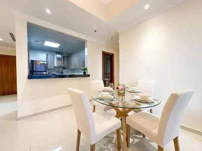 a dining room with a glass table and white chairs at Elegant 1BR in Dunya Tower, Downtown Dubai 12AB10 in Dubai