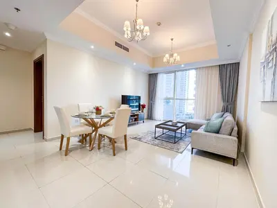 a dining room and living room with a table and chairs at Elegant 1BR in Dunya Tower, Downtown Dubai 12AB10 in Dubai
