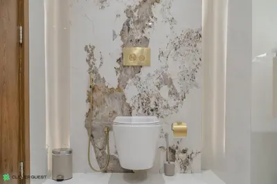 a white toilet in a bathroom with a dirty wall at Clever Guest 028 Baltic in Dubai