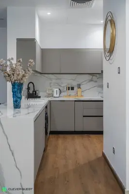 a white kitchen with a vase of flowers on the counter at Clever Guest 028 Baltic in Dubai
