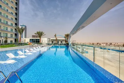 a swimming pool with lounge chairs on a building at Peaceful 1BR in Bella Rose Al Barsha South by Deluxe Holiday Homes in Dubai