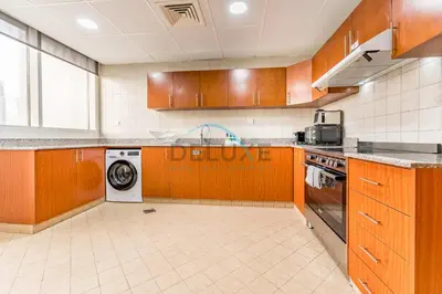 a kitchen with wooden cabinets and a washer and dryer at Stunning 2BR with Assistant Room in MAG 214, Jumeirah Lake Towers by Deluxe Holiday Homes in Dubai