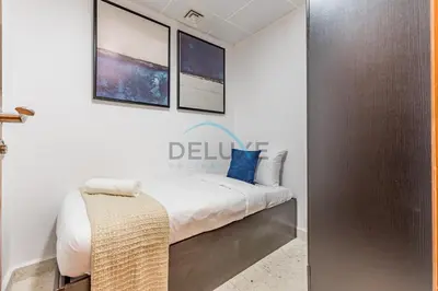 a bedroom with a bed with white sheets and blue pillows at Stunning 2BR with Assistant Room in MAG 214, Jumeirah Lake Towers by Deluxe Holiday Homes in Dubai