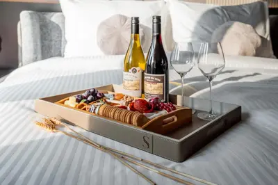 a tray with wine bottles and wine glasses on a bed at Luxury 1-Bedroom Holiday Apartment in Downtown Dubai I Walk to Dubai Mall and Fountains in Dubai