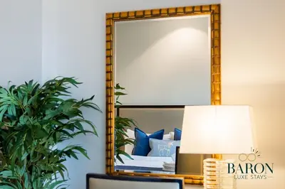 a mirror on a wall next to a bed with blue pillows at The Classic in Dubai