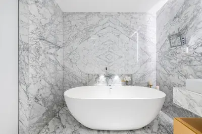 a white tub in a bathroom with marble walls at Grand Dubai Marina 4BR Triplex with Pool Gym Sauna in Dubai