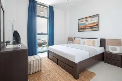a bedroom with a bed with blue curtains and a window at Frank Porter - Pulse C1 in Dubai