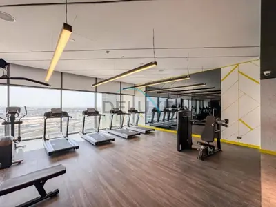a gym with a row of treadmills and machines at Unbeatable Rate Modern 2BR with Partial Canal Views by Deluxe Holiday Homes in Dubai