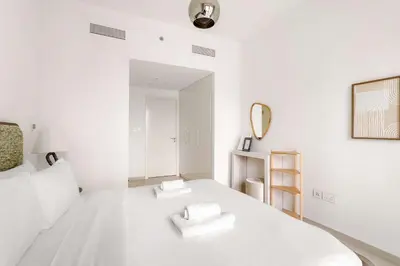 a white bedroom with a white bed and a mirror at Silkhaus Deluxe 2BR in Downtown Views II in Dubai