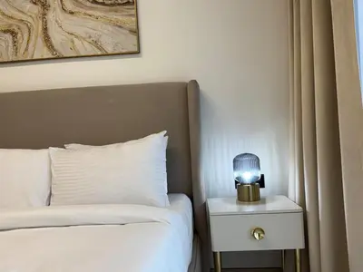 a lamp on a nightstand next to a bed at ASHRI HH Spacious Apartment in JVC, Binghatti Luna in Dubai