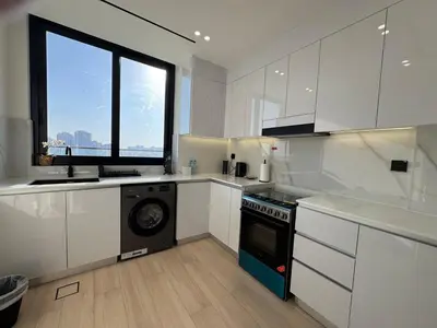 a kitchen with white cabinets and a dishwasher at ASHRI HH Spacious Apartment in JVC, Binghatti Luna in Dubai