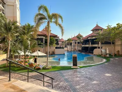 a resort pool with palm trees and people in it at Picture-Perfect 2BR apartment with Burj View in Dubai