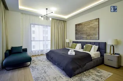 a bedroom with a large bed and a chair at Luxury Escapes - Elegant 3 Bedroom plus Maids Room Apartment in JBR in Dubai