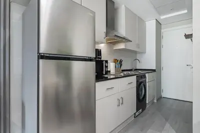 a stainless steel refrigerator in a kitchen with white cabinets at Chic JLT Studio Lake View Metro 5min Marina in Dubai
