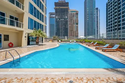 a large swimming pool with chairs and buildings at Chic JLT Studio Lake View Metro 5min Marina in Dubai