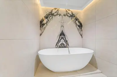 a white tub in a bathroom with a painting on the wall at Burj Khalifa & Fountain From Your Balcony Near Dubai Mall & Metro in Dubai