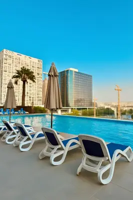 a row of lounge chairs and umbrellas next to a pool at Luxury Burj Khalifa & Canal View Apartment, Business Bay, Downtown Dubai in Dubai