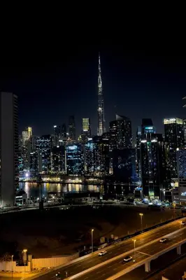 a city skyline at night with a highway in the foreground at Luxury Burj Khalifa & Canal View Apartment, Business Bay, Downtown Dubai in Dubai