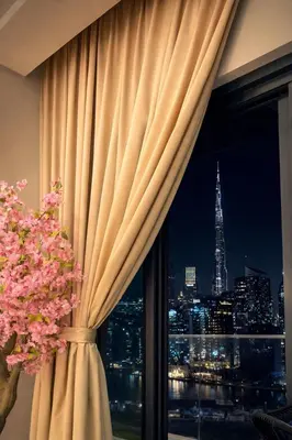 a window with a curtain and a view of the city at Luxury Burj Khalifa & Canal View Apartment, Business Bay, Downtown Dubai in Dubai