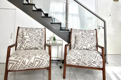 two chairs in a living room with stairs at 2BR Duplex Stunning Views,Near Circle Mall & Park in Dubai
