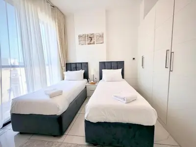 two beds in a room with white walls at 2BR Duplex Stunning Views,Near Circle Mall & Park in Dubai