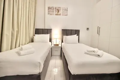two beds in a hotel room with white sheets at 2BR Duplex Stunning Views,Near Circle Mall & Park in Dubai