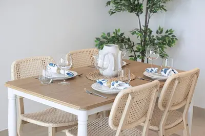 a dining room table with chairs and a wooden table with wine glasses at High Floor Marina Gate 1 Bdr Flat Only Stays in Dubai