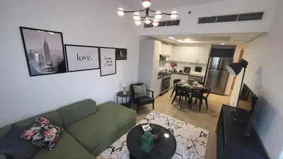 a living room with a green couch and a kitchen at Modern 2BR -5min to Metro-Unit 211 in Dubai