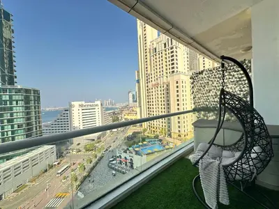 a balcony with a hammock and a view of a city at Opulent Flat with Beach, Pool & Canal View in JBR in Dubai