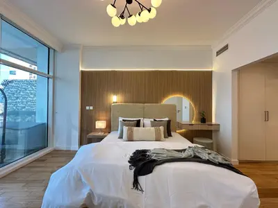 a bedroom with a large bed and a chandelier at Opulent Flat with Beach, Pool & Canal View in JBR in Dubai