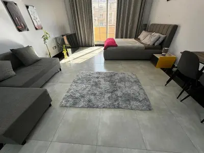 a living room with a couch and a rug on the floor at Specious Fully furnished studio in May residence in Dubai