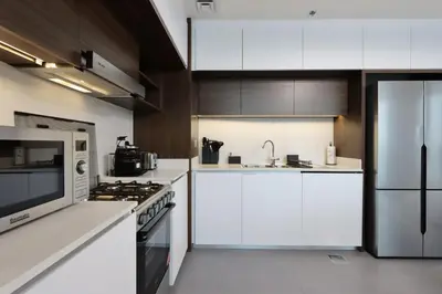 a kitchen with white cabinets and a stainless steel refrigerator at Waterfront 2BR with Dubai Skyline Views in Dubai