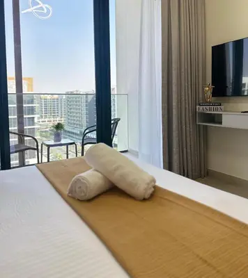 a white towel laying on a bed in a hotel room at Brand New Studio Near Burj khalifa & Dubai Mall in Dubai