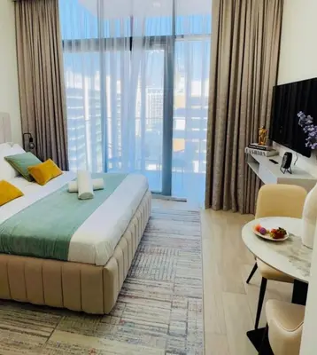 a bedroom with a large bed and a table and a desk at Brand New Studio Near Burj khalifa & Dubai Mall in Dubai
