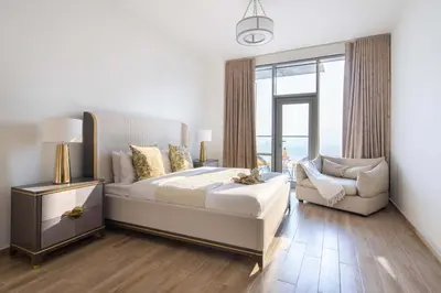 a bedroom with a bed and a chair and a window at Frank Porter - Amna Tower in Dubai