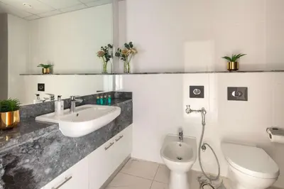 a white bathroom with a sink and a toilet at Frank Porter - Amna Tower in Dubai