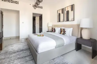 a white bedroom with a large bed and a table at Frank Porter - Tajer Tower E in Dubai