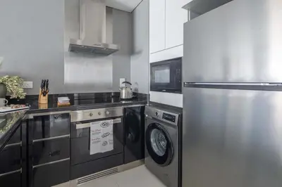 a kitchen with a refrigerator and a washer and dryer at Frank Porter - Damac Heights in Dubai