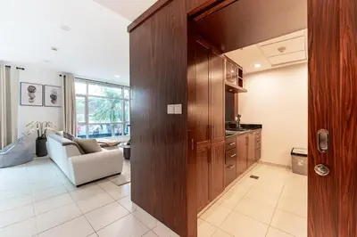 a living room with a couch and a kitchen at Chic 1-Bedroom Getaway with Downtown Living Charm in Dubai
