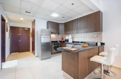 a kitchen with wooden cabinets and a stainless steel refrigerator at 1BHK in central of Dubai Marina in Dubai