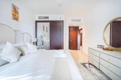 a bedroom with a large white bed with a mirror at 1BHK in central of Dubai Marina in Dubai
