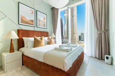 a bedroom with a large bed and a large window at Unit Overlooking Burj Khalifa and Fountain View in Dubai