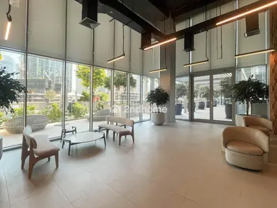 a lobby with chairs and tables and windows at Unit Overlooking Burj Khalifa and Fountain View in Dubai