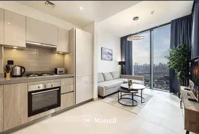 a kitchen and living room with a couch and a table at 1BR Apartment in Sobha Hartland with Skyline Views in Dubai