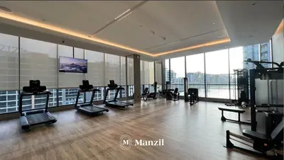 a gym with cardio equipment in a large room with windows at 1BR Apartment in Sobha Hartland with Skyline Views in Dubai