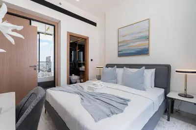 a bedroom with a bed with a table and a window at Sky-High Serenity - Stylish 1BHK - 20th Floor in Dubai