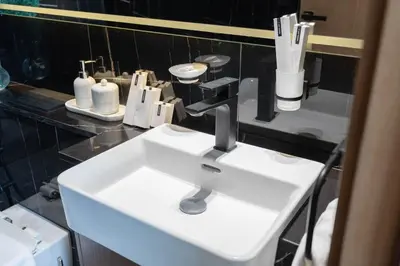 a bathroom with a white sink and a black counter at Sky-High Serenity - Stylish 1BHK - 20th Floor in Dubai
