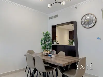 a dining room table with chairs and a clock on the wall at Rare Holiday Homes - Marina Quays West Tower - Near the Beach - R1003 - Dubai Marina in Dubai