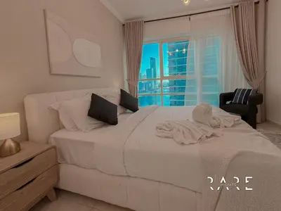 a bedroom with a large white bed with a window at Rare Holiday Homes - Marina Quays West Tower - Near the Beach - R1003 - Dubai Marina in Dubai