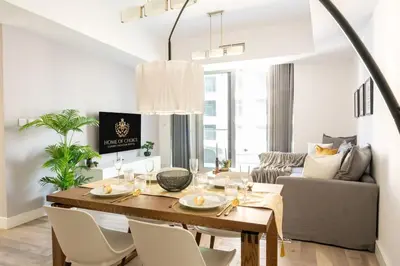 a dining room with a table and a couch at Damac Waves Tower Dubai Marina - By Home Of Choice in Dubai